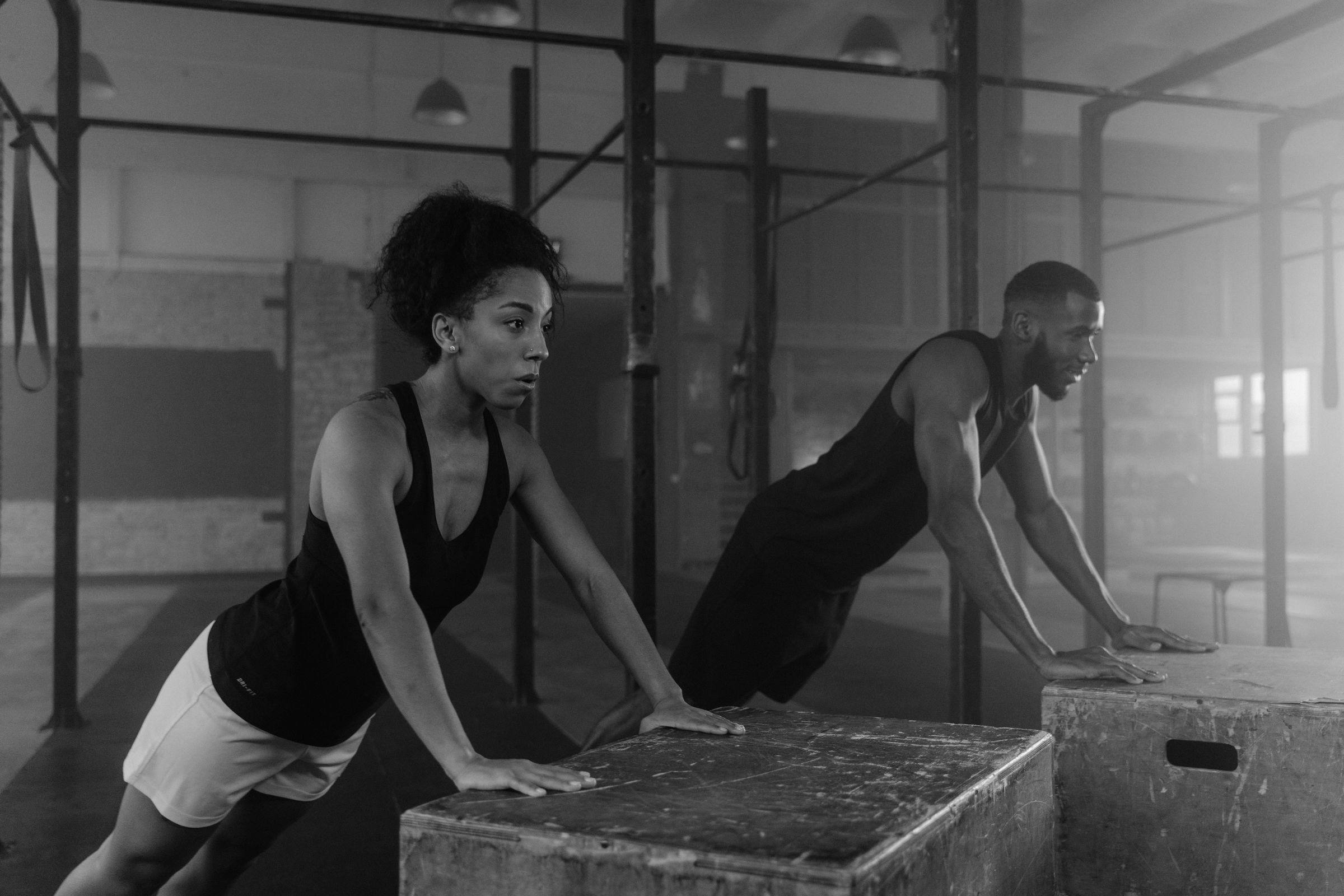 Two athletes doing push-ups on plyo boxes in black and white