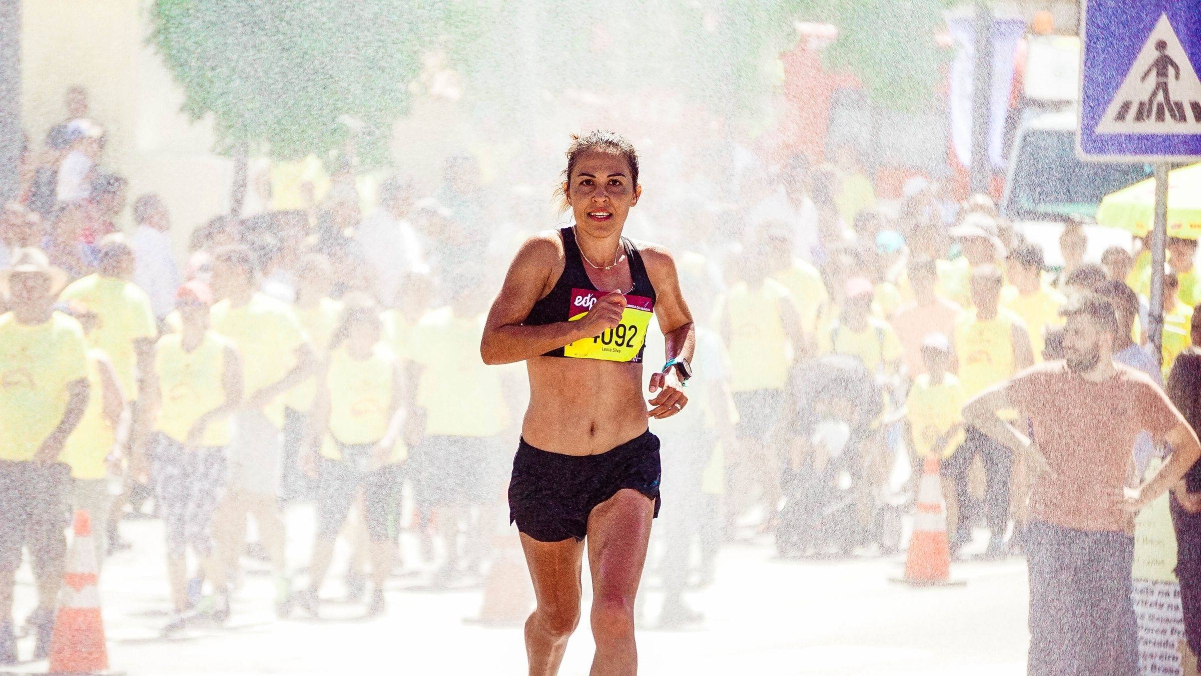 Runner smiling through a misting station as a crowd cheers
