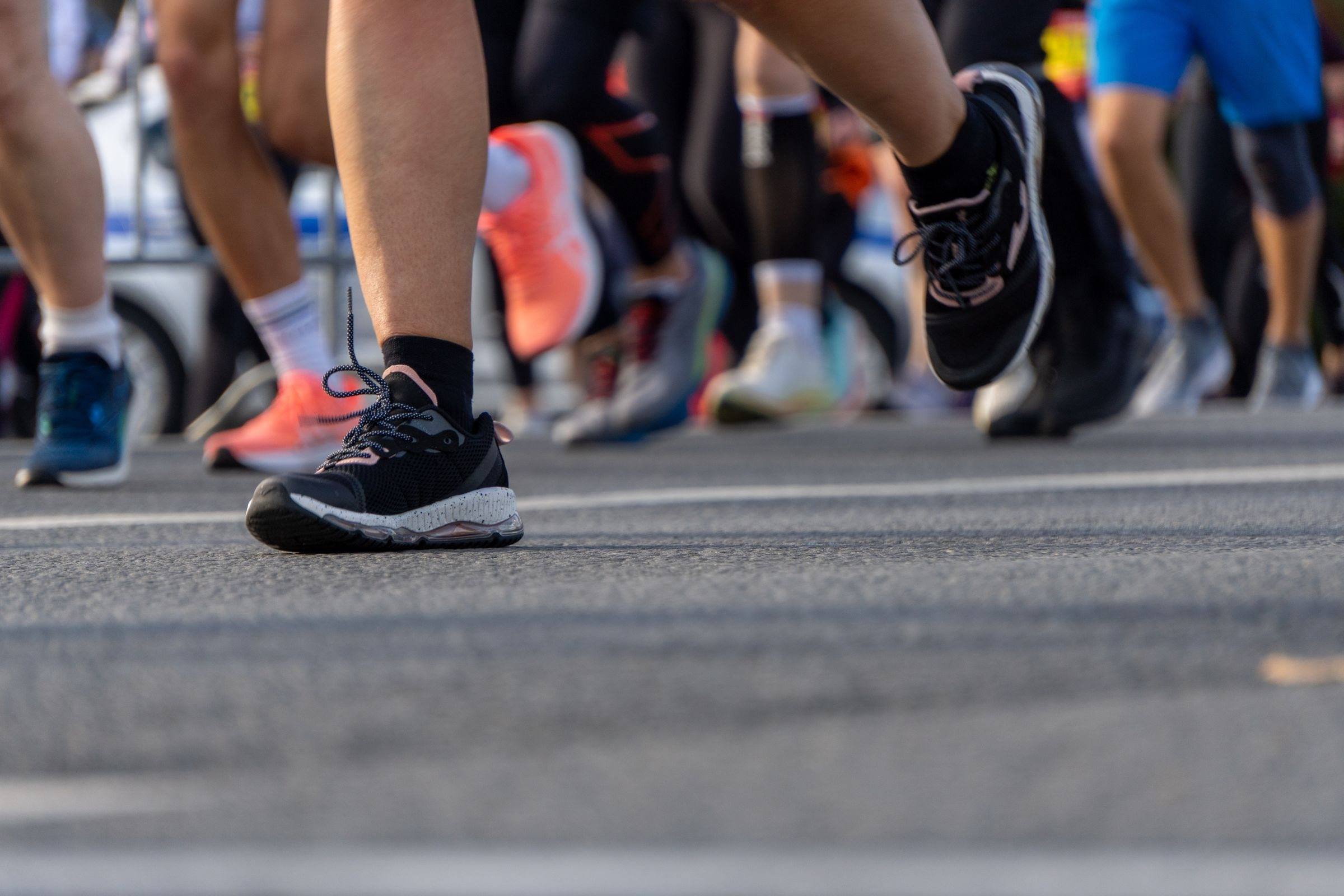 Close-up of runners’ shoes at the start of a road race