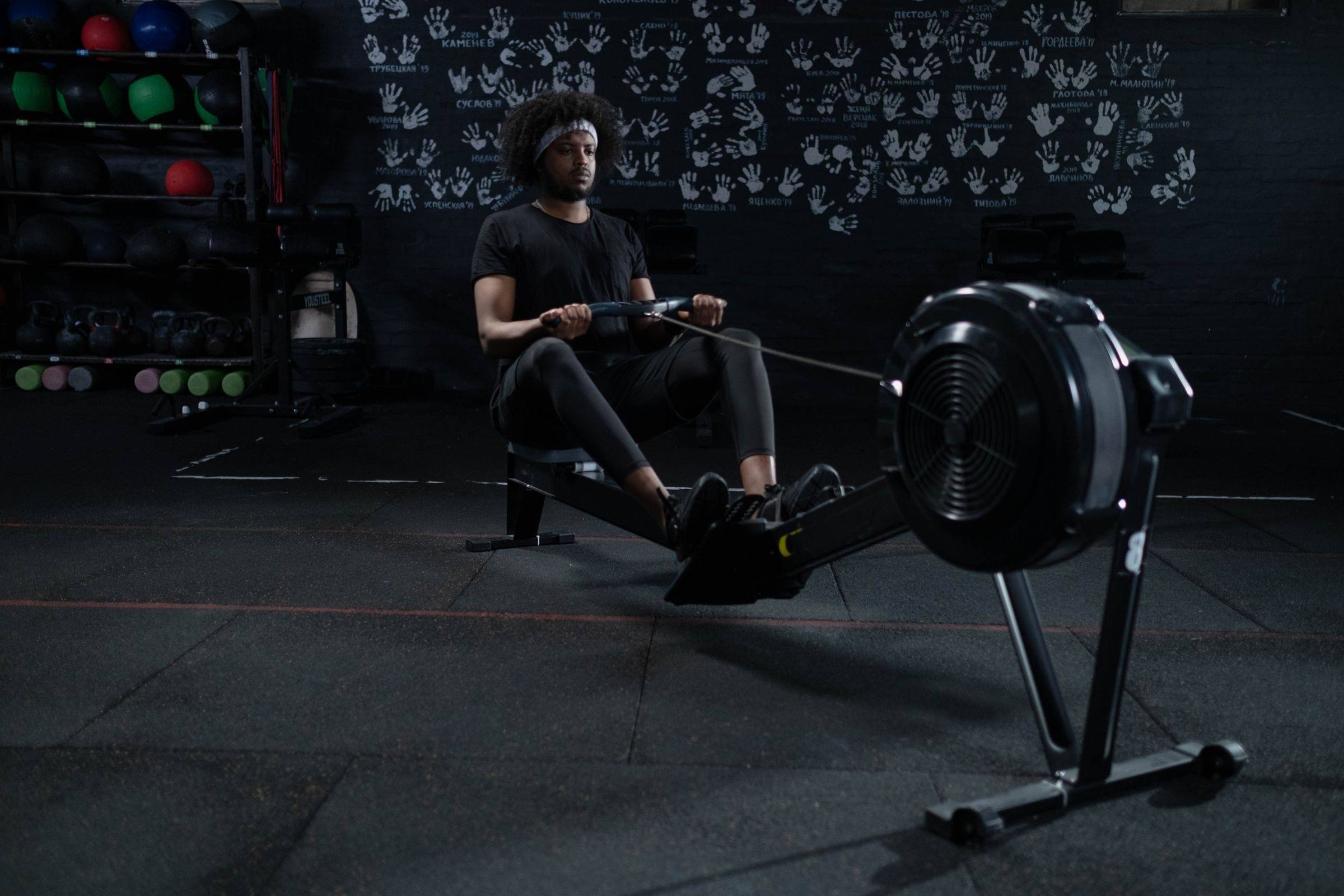 Athlete driving through a stroke on a rowing machine in a dark gym