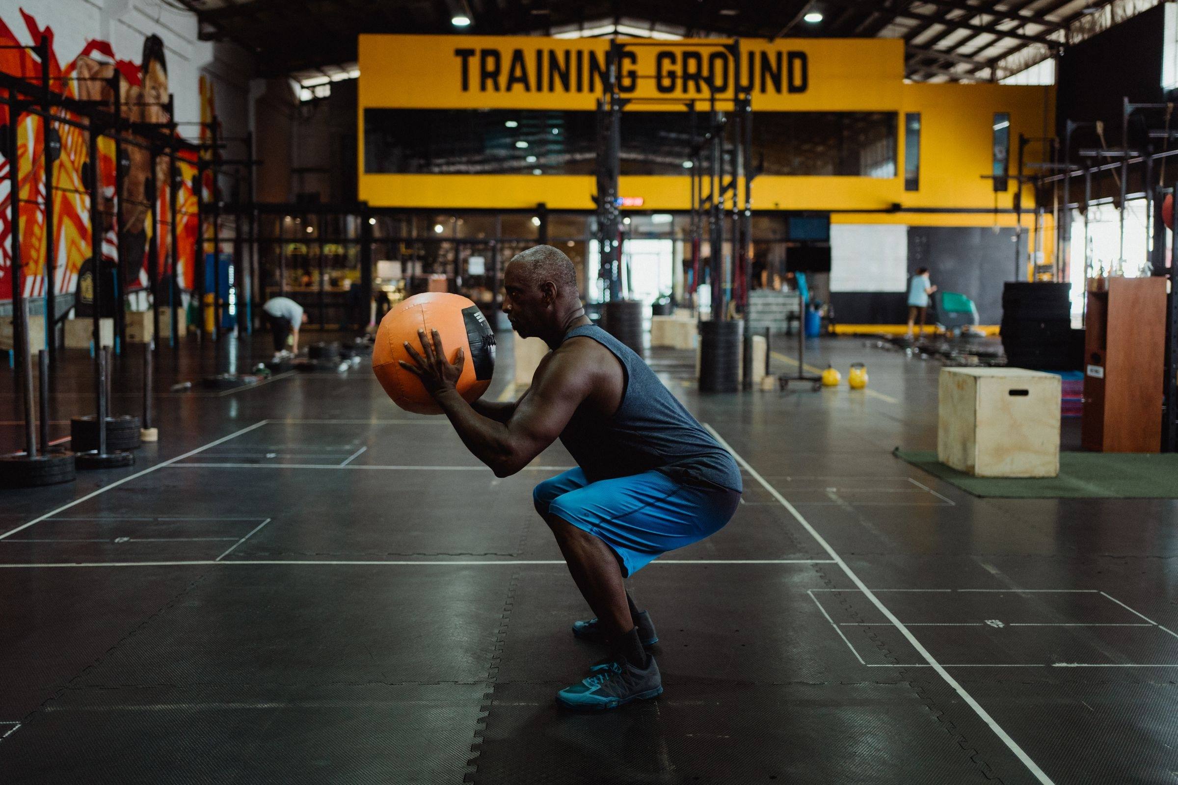 Athlete squatting with a medicine ball in a functional fitness gym